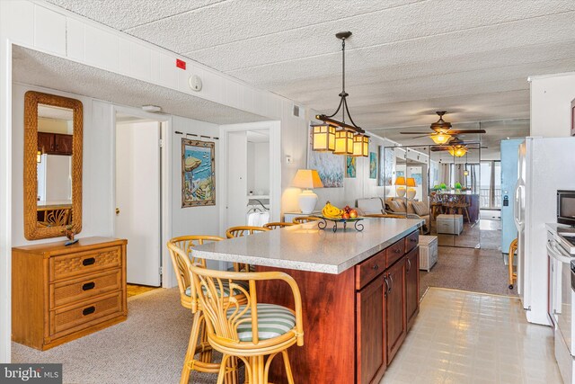 kitchen with white refrigerator, ceiling fan, a kitchen island, pendant lighting, and white fridge with ice dispenser