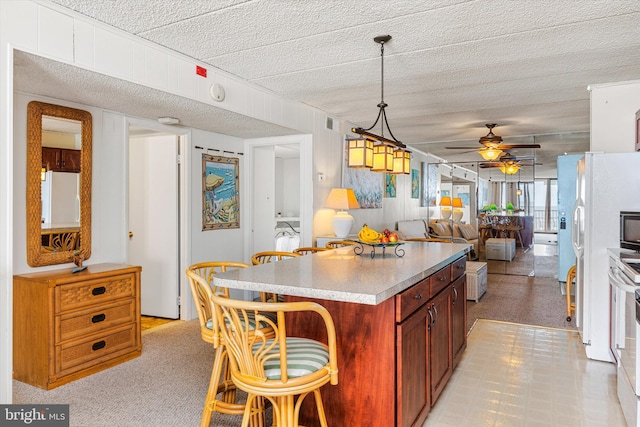 kitchen with a breakfast bar area, a ceiling fan, white refrigerator, open floor plan, and a center island