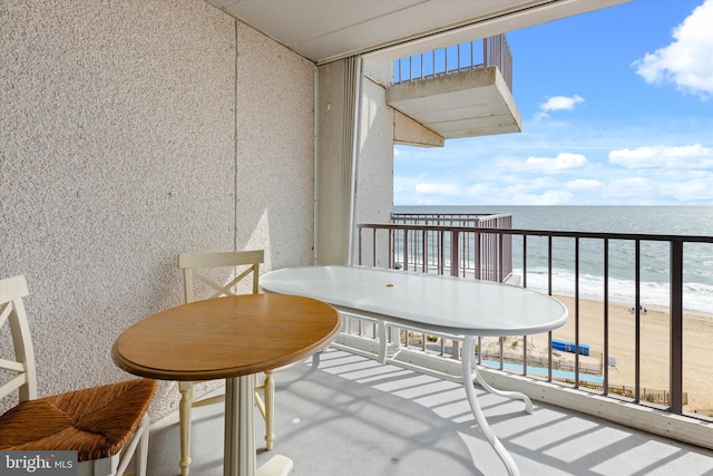 balcony featuring a view of the beach and a water view