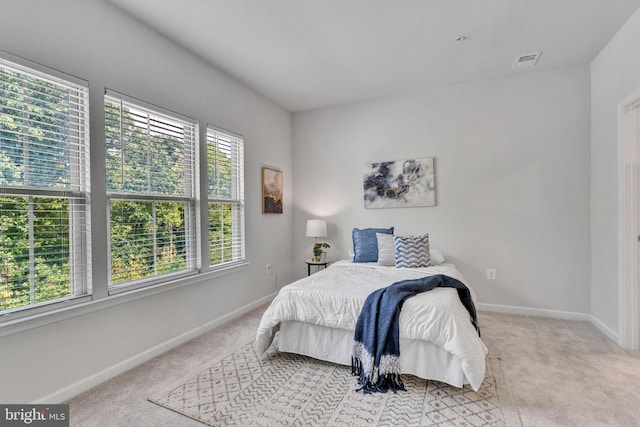 bedroom featuring light carpet and multiple windows