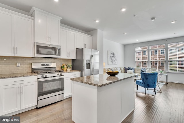 kitchen featuring light stone counters, light hardwood / wood-style flooring, stainless steel appliances, and white cabinetry