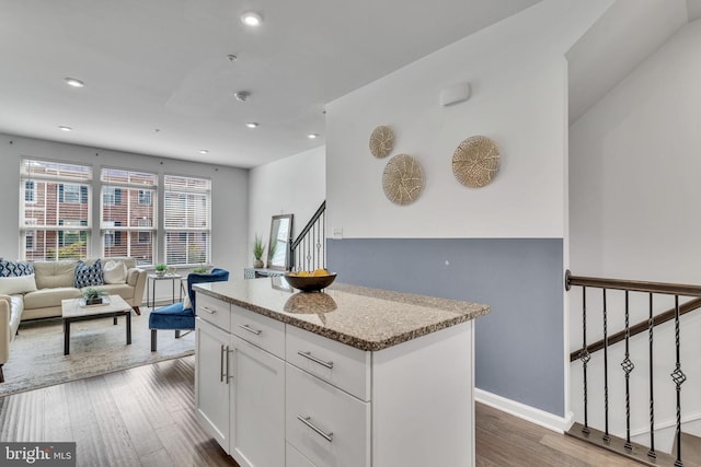 kitchen featuring a kitchen island, light stone countertops, white cabinetry, and dark hardwood / wood-style flooring