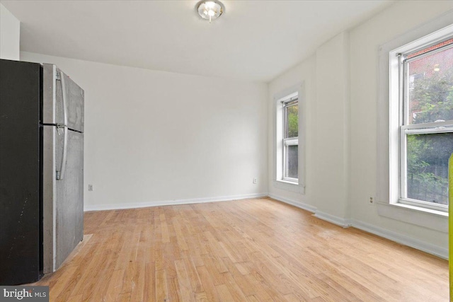 spare room featuring light wood-type flooring and a healthy amount of sunlight