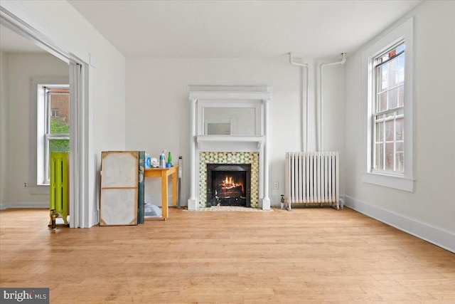 unfurnished living room featuring radiator, light hardwood / wood-style floors, and a fireplace