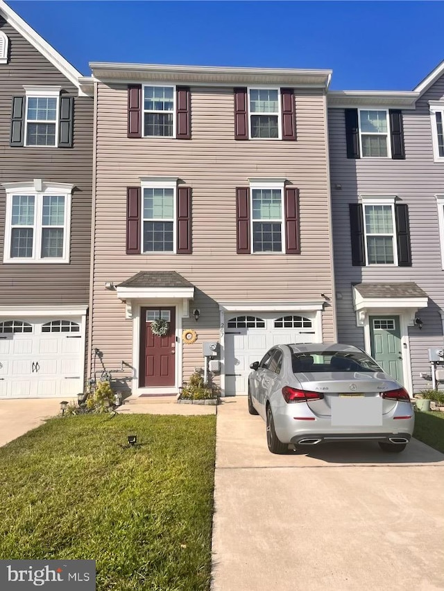 townhome / multi-family property with a front lawn and a garage