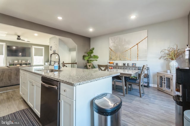 kitchen featuring hardwood / wood-style floors, white cabinets, dishwasher, an island with sink, and sink