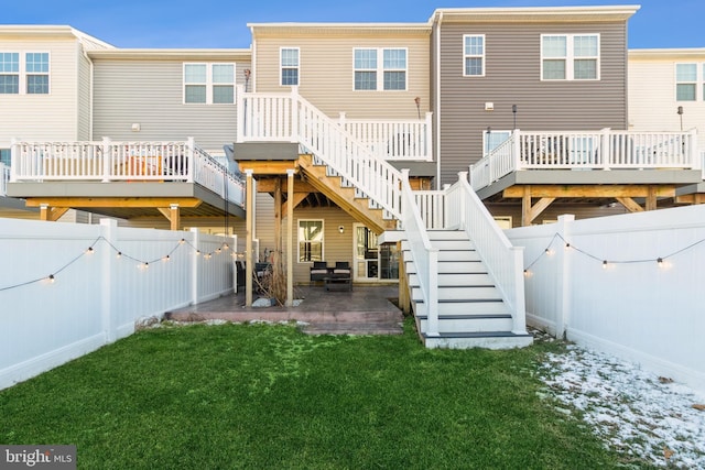 back of house featuring a lawn, a deck, and a patio