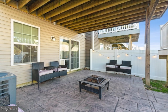 view of patio with central AC unit and an outdoor living space with a fire pit