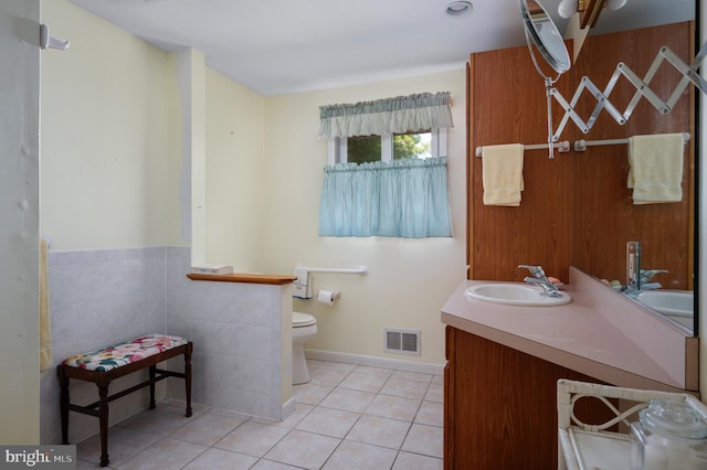 bathroom featuring tile patterned floors, vanity, tile walls, and toilet