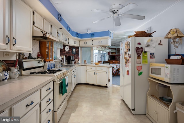 kitchen with kitchen peninsula, white appliances, ceiling fan, sink, and white cabinetry