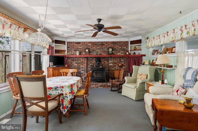 dining room featuring a wood stove, carpet floors, and ceiling fan with notable chandelier