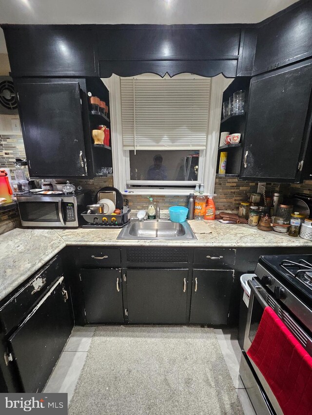 kitchen featuring stainless steel appliances, sink, light tile patterned floors, and backsplash