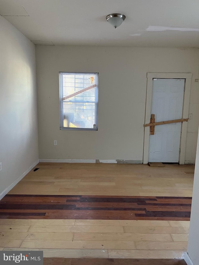 spare room with baseboards and hardwood / wood-style floors