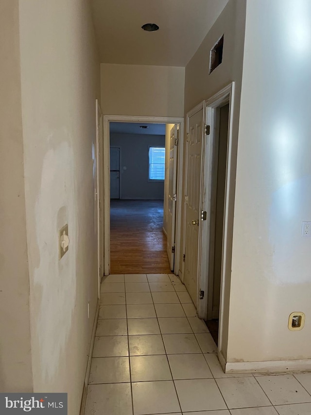 corridor with light tile patterned floors and baseboards