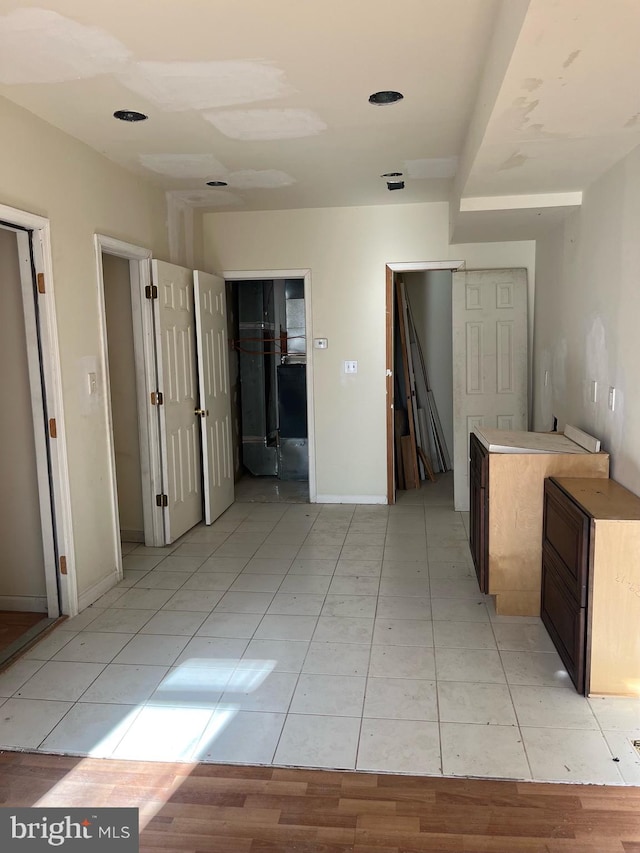 hall featuring light tile patterned floors and baseboards