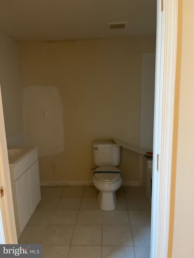 bathroom featuring vanity, baseboards, visible vents, tile patterned floors, and toilet