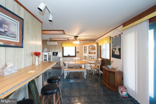 dining space featuring rail lighting, an AC wall unit, wooden walls, and plenty of natural light