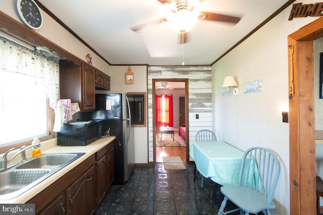 kitchen with dark brown cabinets, crown molding, black microwave, light countertops, and a sink