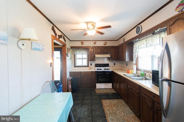 kitchen featuring a sink, under cabinet range hood, gas range oven, freestanding refrigerator, and light countertops