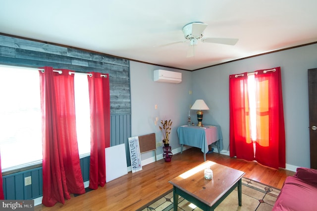 living room with a wall mounted air conditioner, baseboards, and wood finished floors