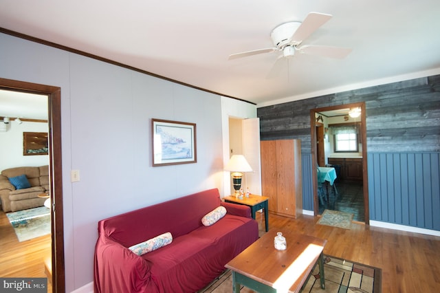 living area with a ceiling fan, crown molding, and wood finished floors