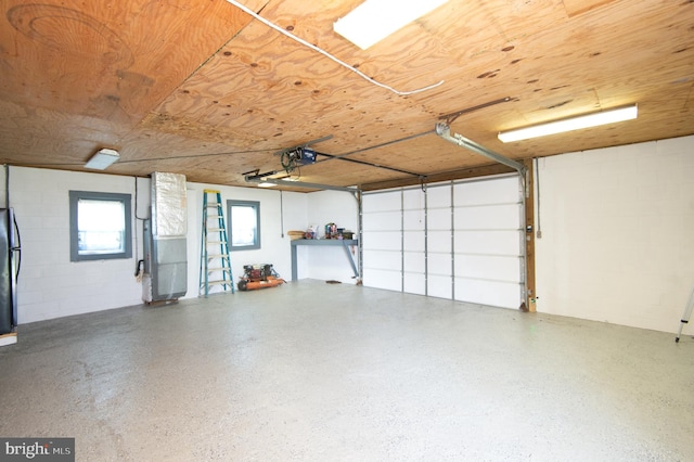 garage with heating unit, a garage door opener, freestanding refrigerator, concrete block wall, and wood ceiling