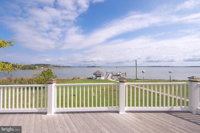 wooden terrace featuring a water view and a lawn