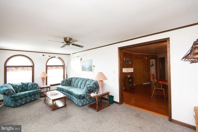 carpeted living room featuring a ceiling fan, crown molding, and baseboards