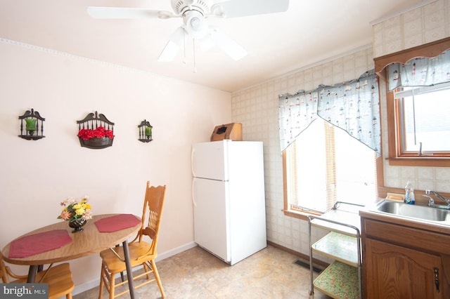 kitchen featuring visible vents, ceiling fan, baseboards, freestanding refrigerator, and a sink