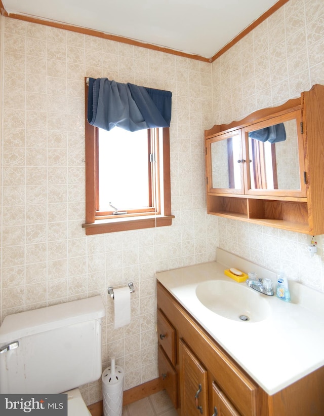 bathroom with toilet, tile walls, ornamental molding, and vanity