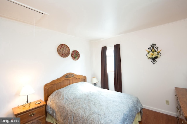 bedroom featuring attic access, baseboards, and wood finished floors