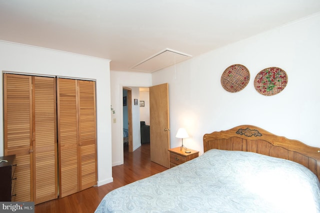 bedroom with a closet, ornamental molding, attic access, and wood finished floors