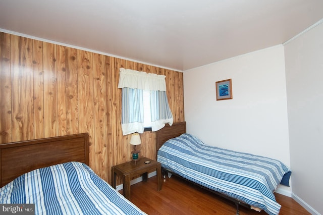bedroom with crown molding, baseboards, and wood finished floors