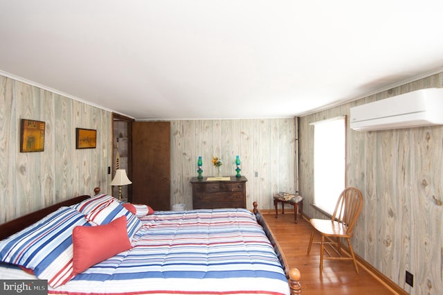 bedroom with baseboards, a wall unit AC, and wood finished floors