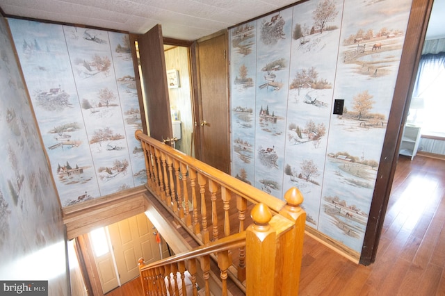 hallway with stairway, wood finished floors, and wallpapered walls