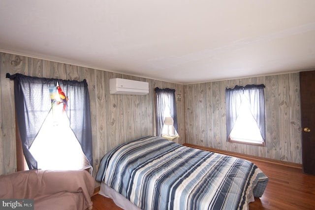 bedroom featuring baseboards, wood finished floors, and a wall mounted AC