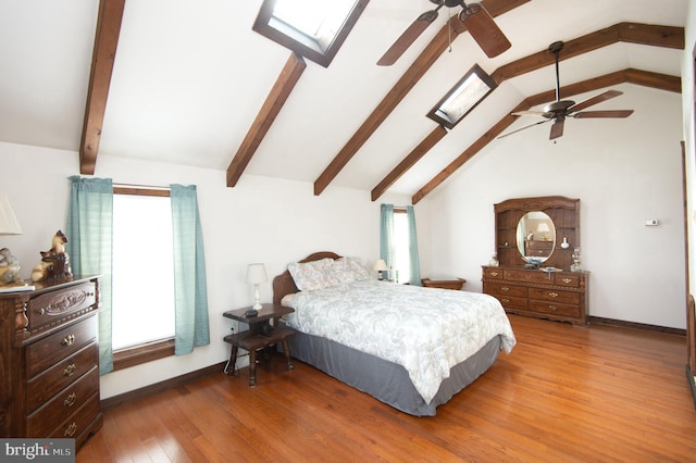 bedroom with ceiling fan, baseboards, lofted ceiling with skylight, and wood finished floors