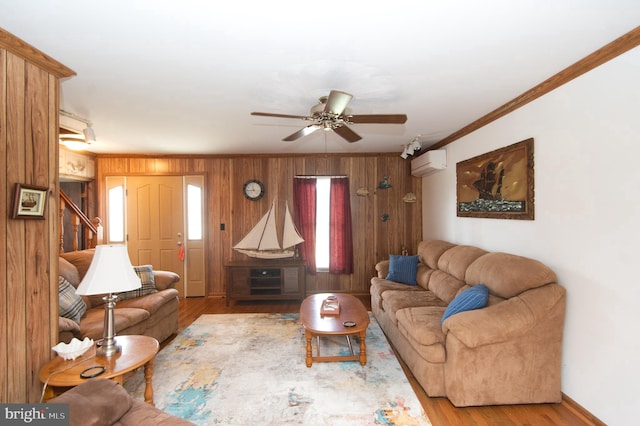 living area with wood finished floors, a wall mounted AC, ceiling fan, ornamental molding, and wood walls