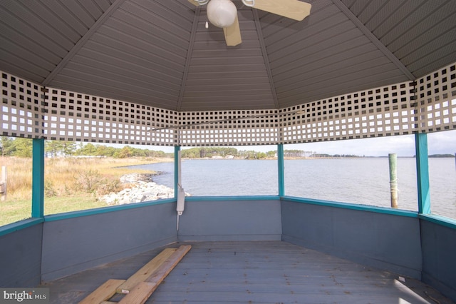 unfurnished sunroom with plenty of natural light, a ceiling fan, and a water view