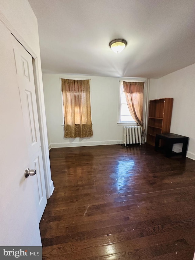 unfurnished room featuring radiator, baseboards, and wood finished floors