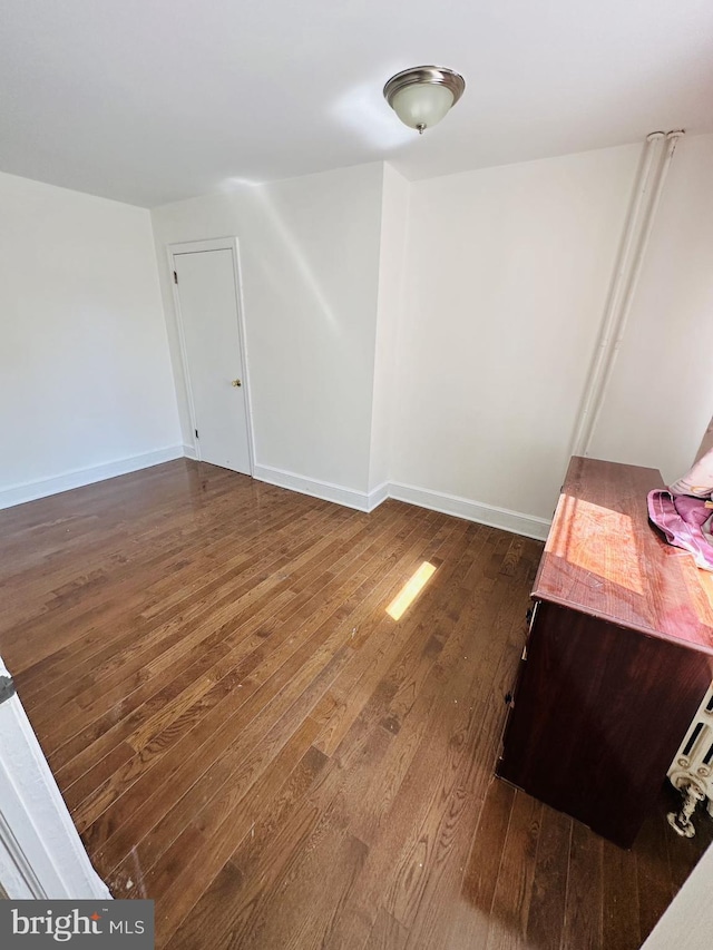 spare room featuring dark wood-type flooring and baseboards