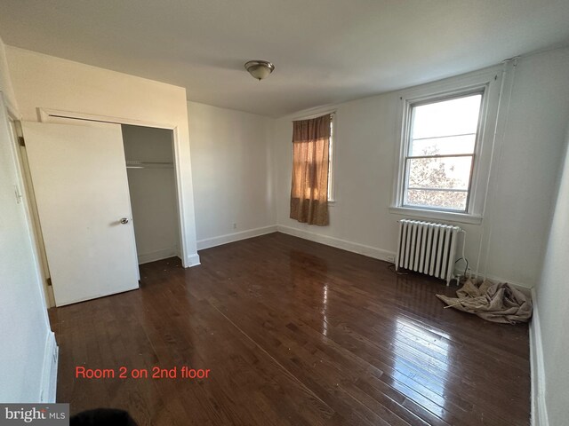 unfurnished room featuring baseboards and dark wood-type flooring