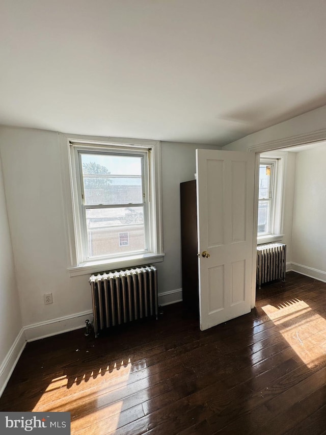 unfurnished bedroom with hardwood / wood-style flooring, radiator, and baseboards