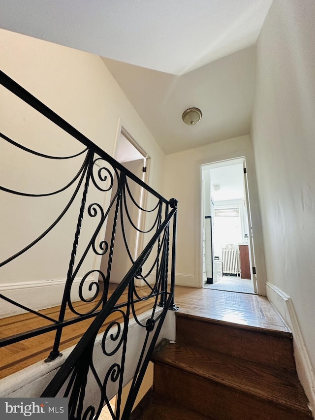 staircase featuring baseboards and wood finished floors