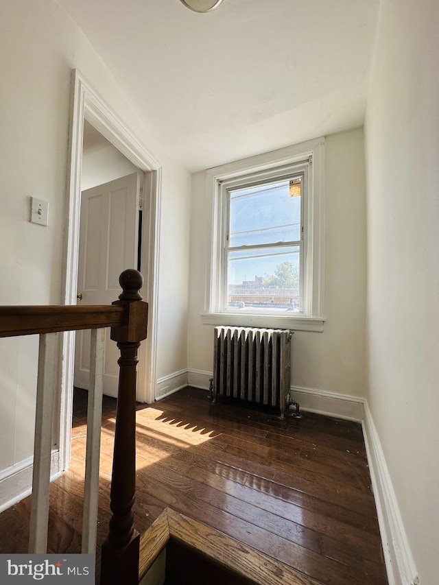 empty room featuring hardwood / wood-style flooring, radiator, and baseboards