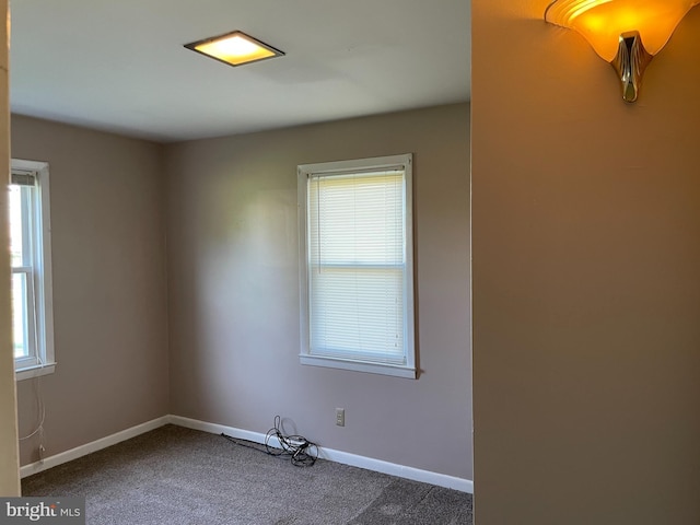 empty room with baseboards and dark colored carpet