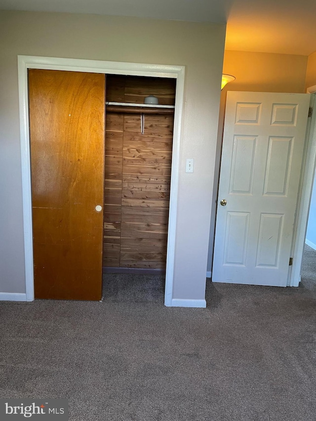 unfurnished bedroom featuring a closet, baseboards, and carpet