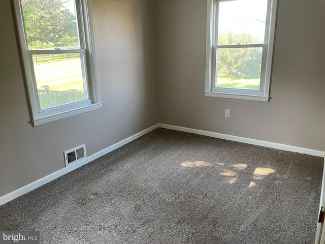 carpeted empty room featuring baseboards and visible vents