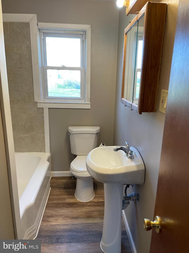 bathroom featuring wood finished floors, baseboards, toilet, a shower, and a bath