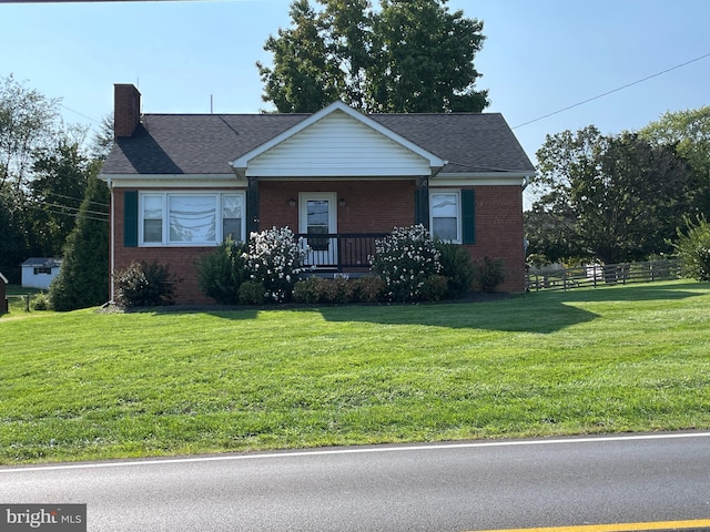 view of front of house with a front lawn, brick siding, a chimney, and fence